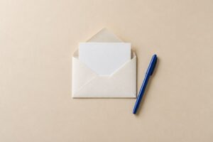 アンケートの依頼をイメージした白い封筒と便箋、青いペン